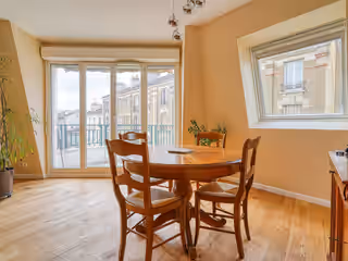 Le même séjour : parquet en chêne, murs repeints, table de salle à manger devant la baie
