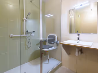 Salle de bain adaptée : douche de plain-pied, barres d’appui, siège rabattable, lavabo accessible