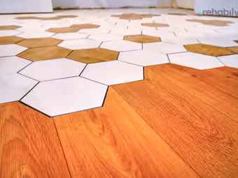 Jonction entre un parquet en bois et des carreaux hexagonaux blancs et bois, en gros plan