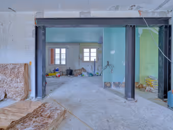 Rez-de-chaussée en chantier : portique en acier posé à la place d’un mur porteur, sol et murs bruts