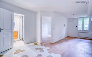 Appartement rénové au Pré-Saint-Gervais : porte moulurée blanche, parquet qui rejoint des carreaux hexagonaux